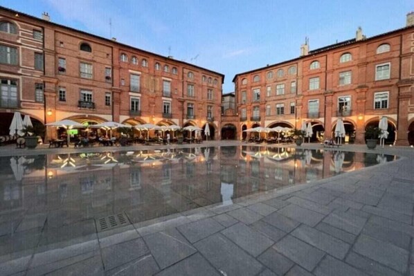 A courtyard with a reflective pool, red brick buildings, and outdoor seating areas. - Deltour Hotel Montauban City (Montauban)