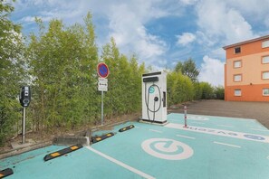 An electric vehicle charging station with a no parking sign, a speed camera, and a building in the background. - Deltour Hotel Montauban City (Montauban)