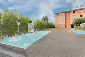A parking area with electric vehicle charging stations, a hotel building, and a sign indicating no parking. - Deltour Hotel Montauban City (Montauban)