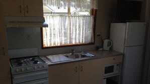 A compact kitchen with a gas stove, a sink, a microwave, and a refrigerator. - Blue Dolphin Holiday Resort (Yamba)