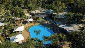 A resort with a large swimming pool, palm trees, and multiple buildings. - Blue Dolphin Holiday Resort (Yamba)