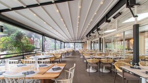 A spacious restaurant with high ceilings, large windows, and a modern interior design. Tables are neatly arranged with chairs, and the space is well-lit. - Club Belambra La Grande Motte (La Grande-Motte)