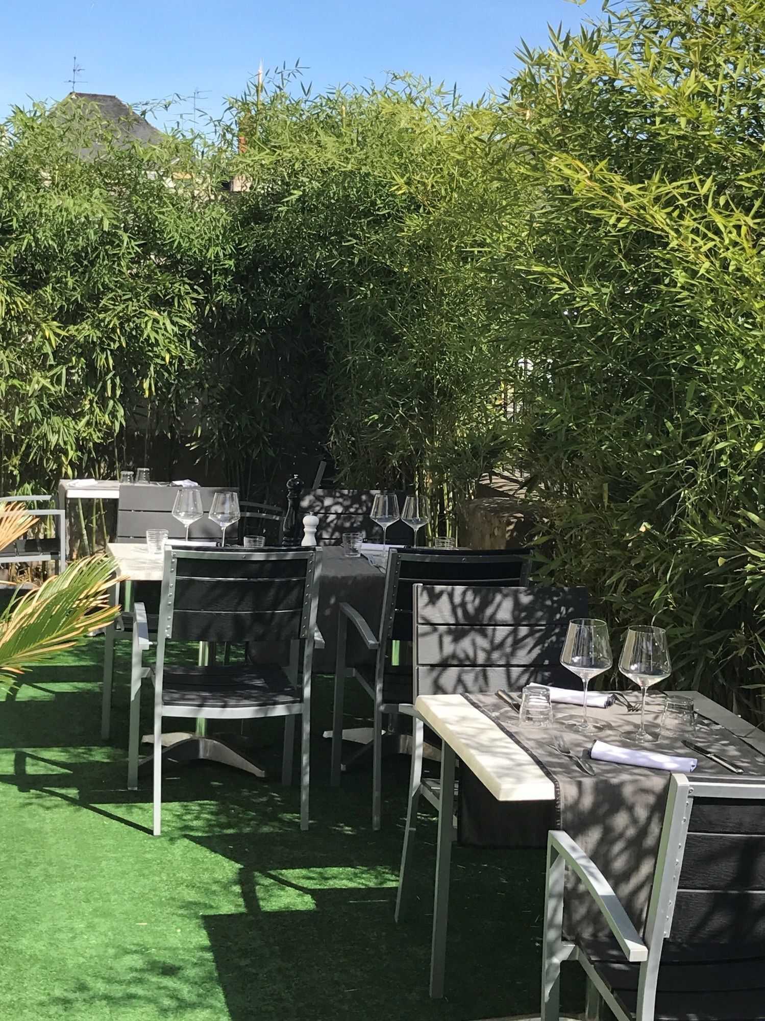 An outdoor dining area with tables and chairs, surrounded by greenery and a mountain in the background.