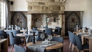 A restaurant with stone walls, round tables, and modern chairs.