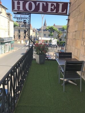 A hotel balcony with artificial grass, a potted plant, and a metal railing. - Citotel Le Chapon Fin (Brive-la-Gaillarde)