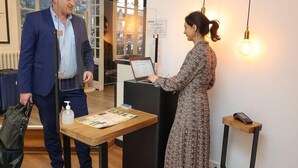 A reception desk with a laptop, a printed map, and a small table with a bottle.
