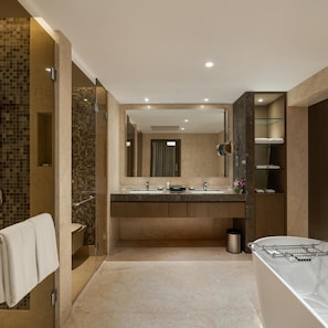A modern bathroom with a glass shower enclosure, a large mirror, a marble sink, and a built-in towel rack. - Palm Meadows Resort (Bengaluru)