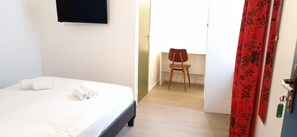 Una habitación de hotel con una cama, una silla y una puerta con cortina roja.