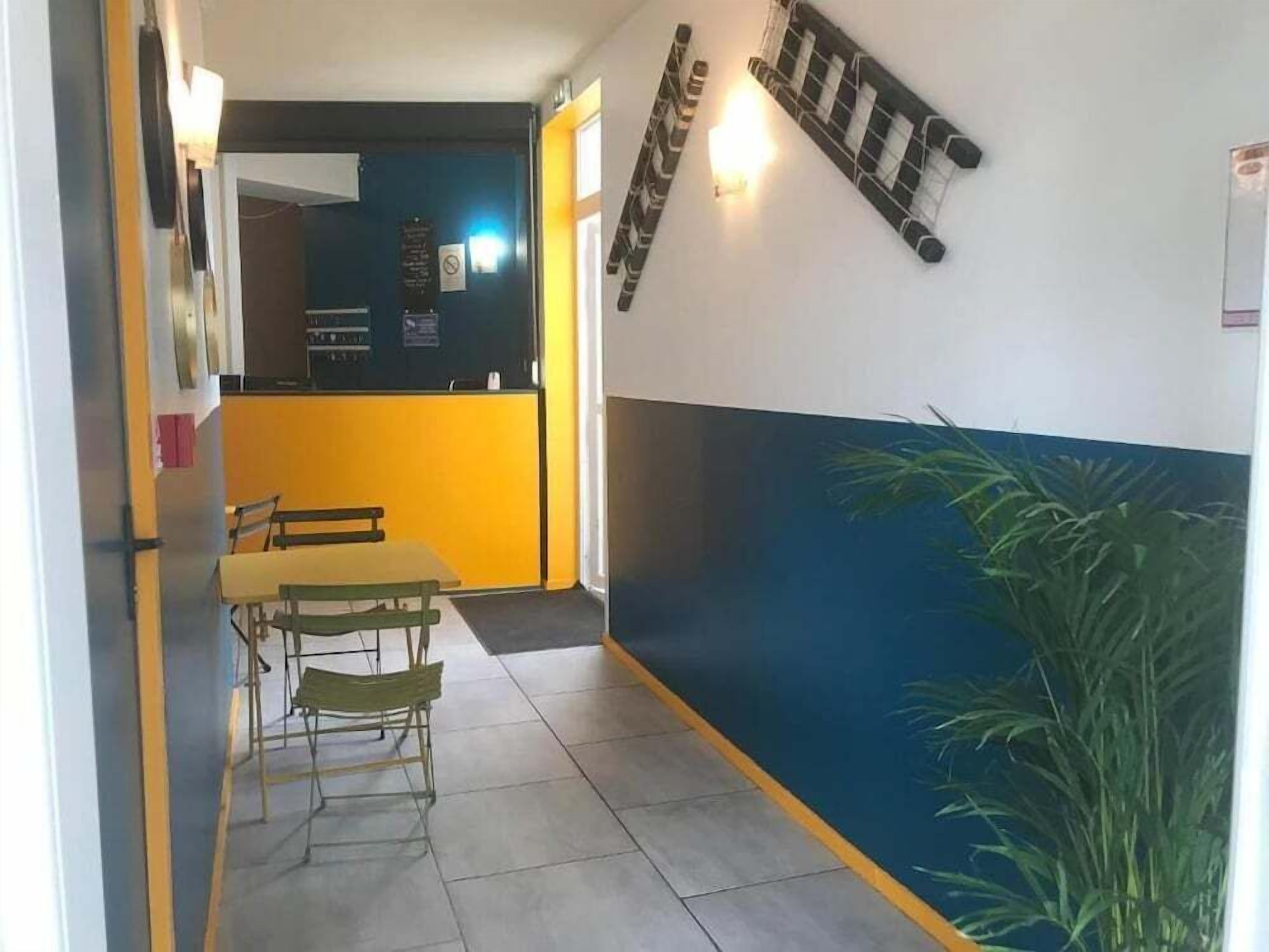 A hallway with a yellow counter, a table with chairs, and a blue wall with a plant.