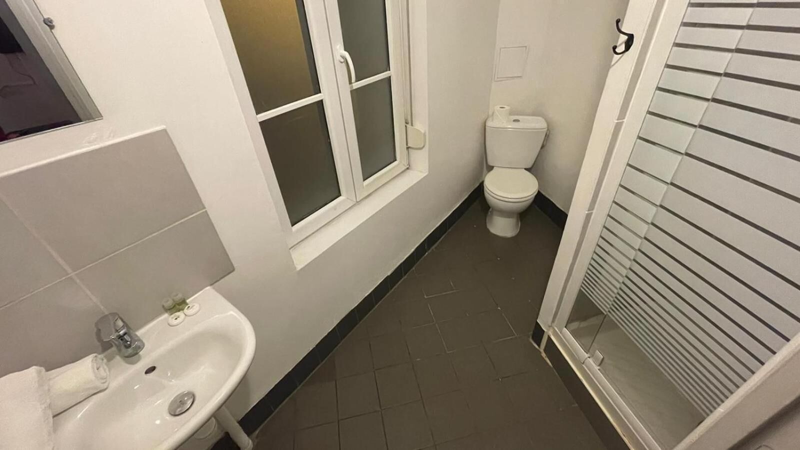 A bathroom with a sink, toilet, and window.