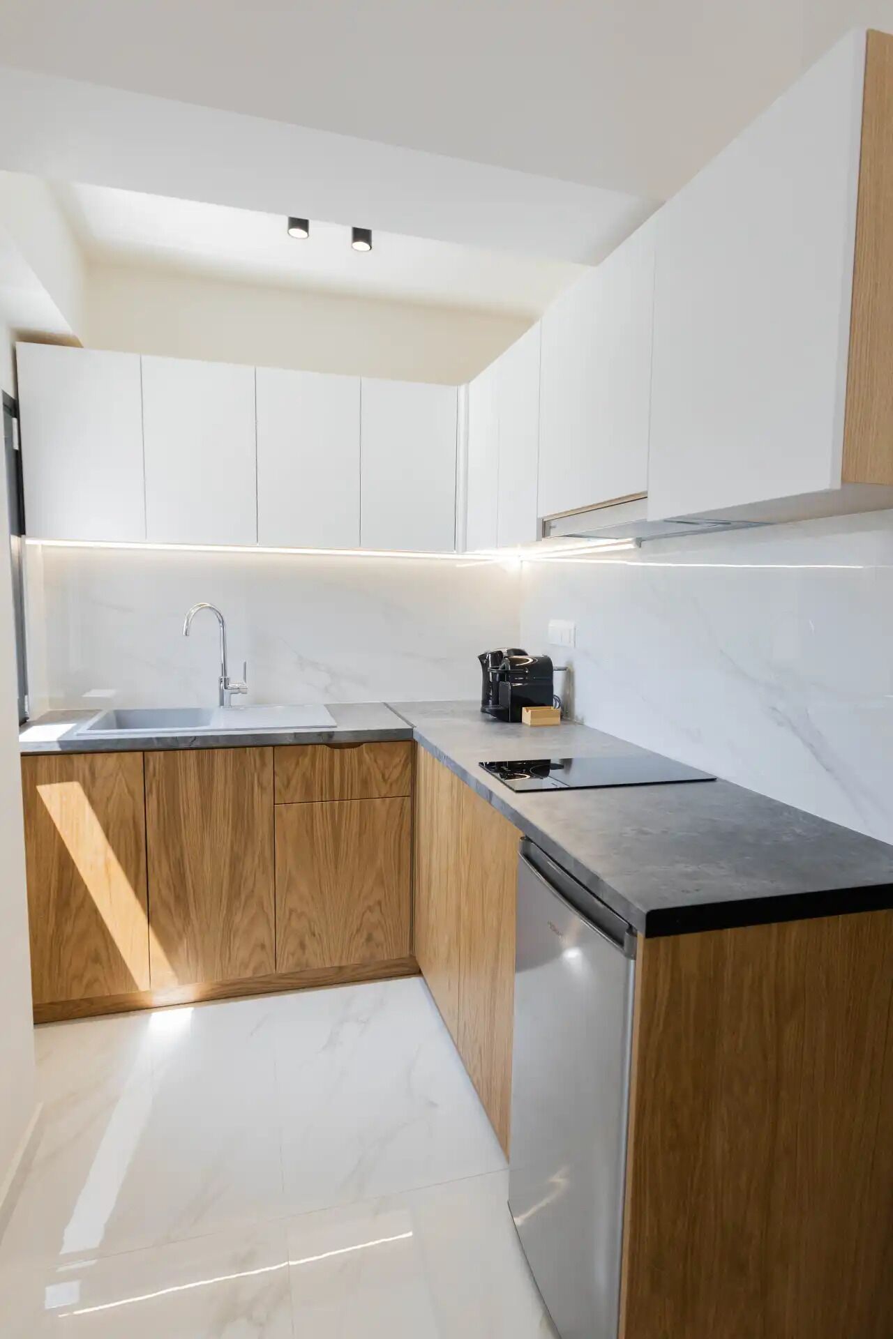 A modern kitchen with white cabinets, a wooden countertop, and a stainless steel sink.