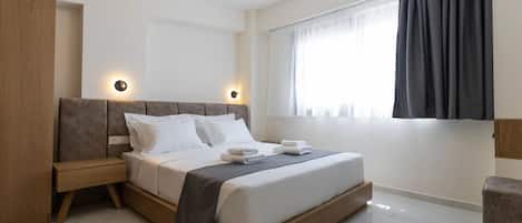 A modern bedroom with a large bed, bedside tables, and a window with curtains.