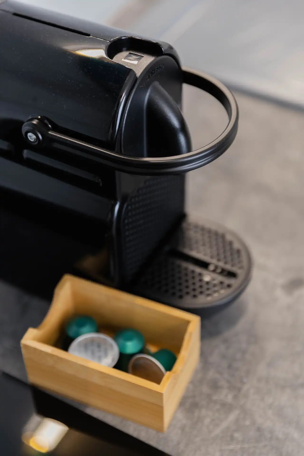 A coffee machine with a wooden box containing several coffee pods.