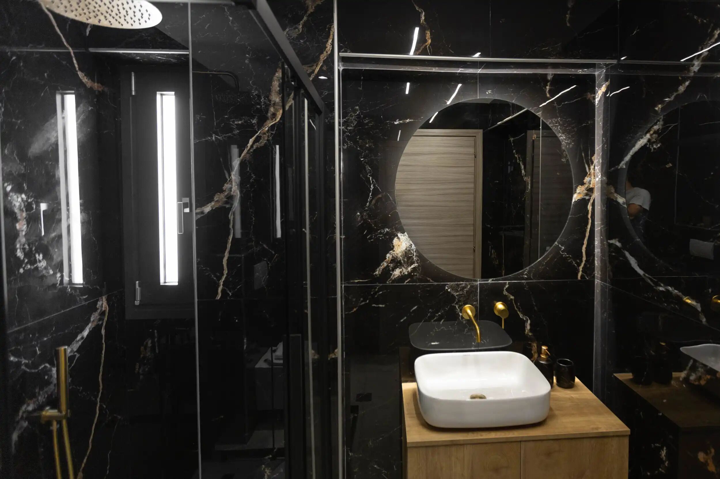 A modern bathroom with a large mirror, a white sink, and a shower area.
