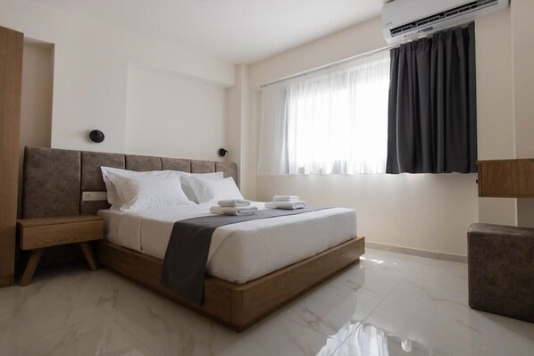 A modern bedroom with a wooden bed, a nightstand, a bedside table, a window with curtains, and an air conditioning unit.