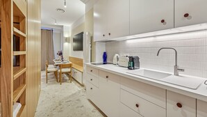 Eine moderne Küche mit weißen Schränken, einer eingebauten Spüle und einem Essbereich mit Tisch und Stühlen.