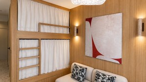 Ein Zimmer mit Holzwand, einer Couch mit gemusterten Kissen, einem großen abstrakten Gemälde und einer Wandleuchte.