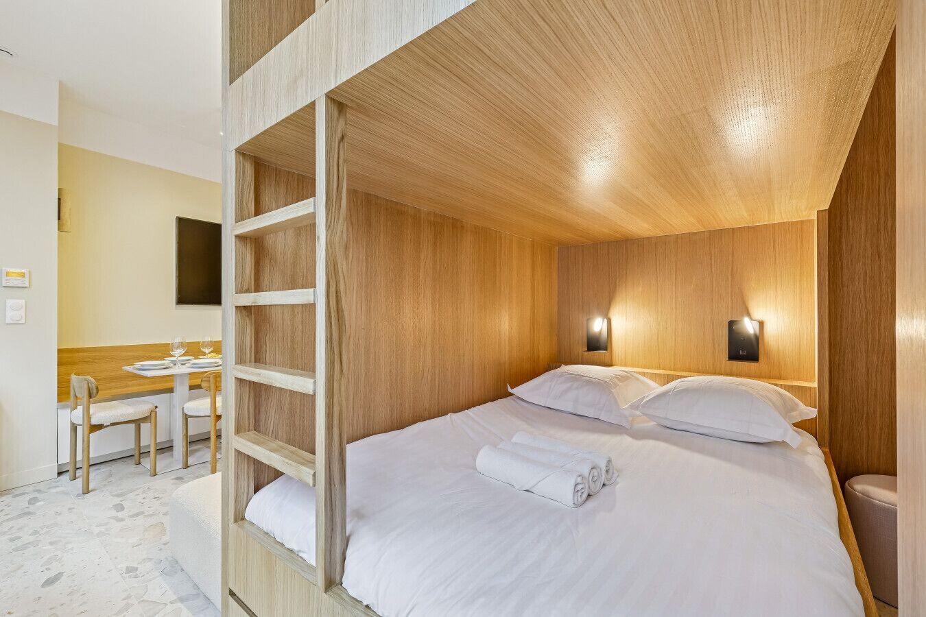 A room with a bunk bed, a desk with chairs, and a small table with glasses.