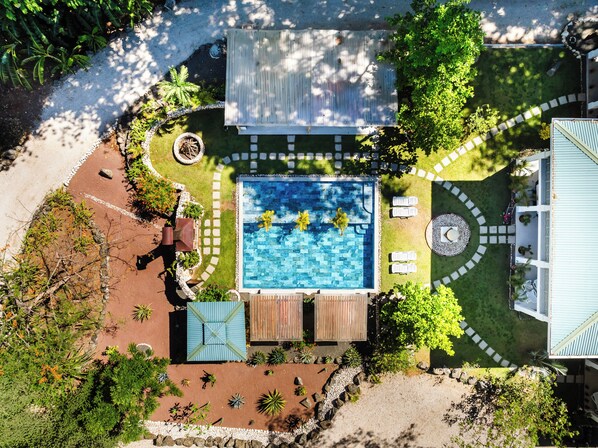 An aerial view of a residential property with a swimming pool, patio furniture, and a garden area. - Buendía Lux • Villa Harmonia. Stunning 3 king beds with pool near the beach. (Potrero)