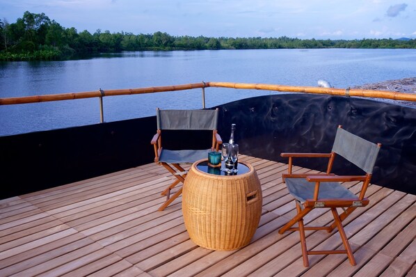 A deck with two wooden chairs, a woven round table, and a bottle of champagne. - Yathra Houseboat By Jetwing (Bentota)
