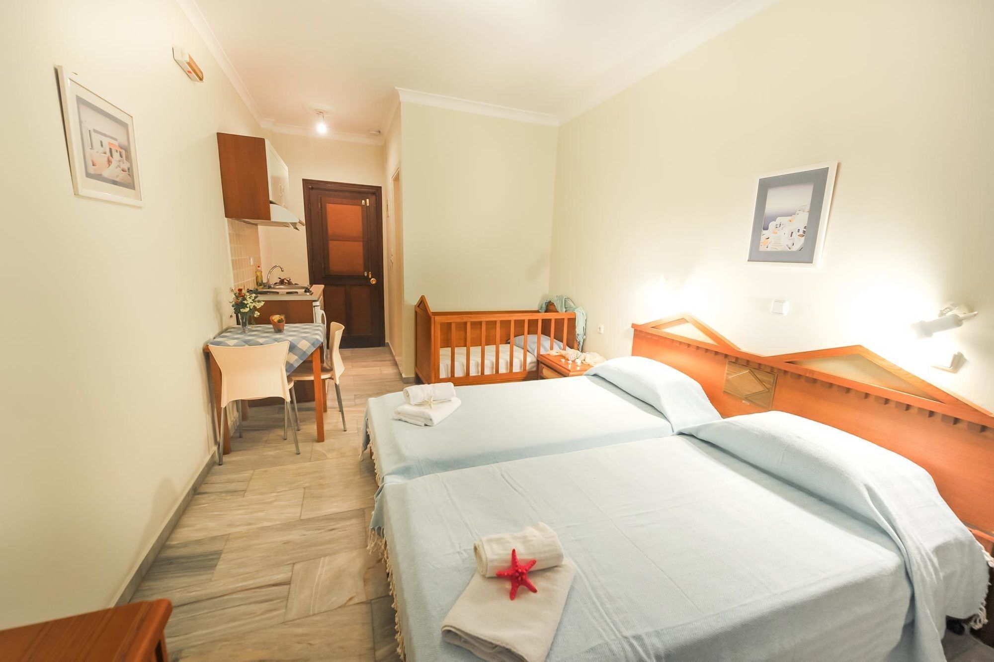 A hotel room with two beds, a desk, and a small kitchenette.