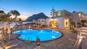 Zona de piscina con sillas de descanso y un restaurante llamado "Kalypso" en un entorno costero.