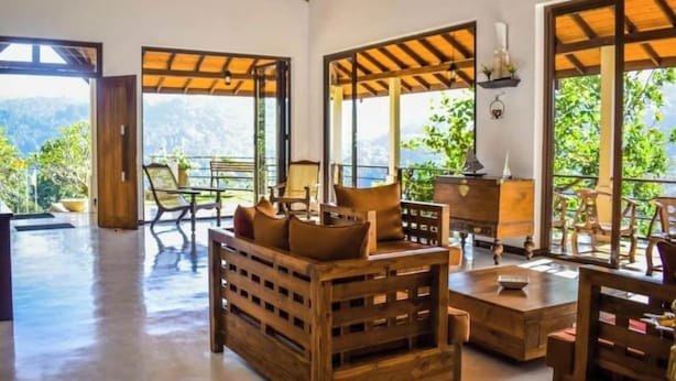 A spacious room with wooden furniture, large windows, and a view of greenery. - Aqua Dunhinda Villa & Nature Retreat (Gampola)