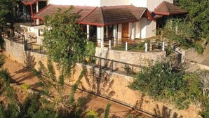 A modern two-story building with a flat roof and multiple red-roofed structures attached. - Aqua Dunhinda Villa & Nature Retreat (Gampola)