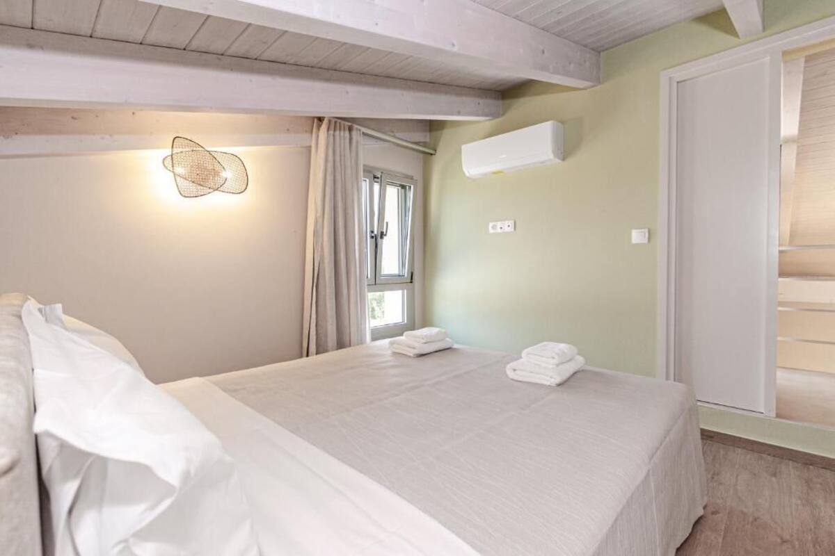 Un dormitorio con cama, ventana, aire acondicionado instalado en la pared y lámpara en el techo.