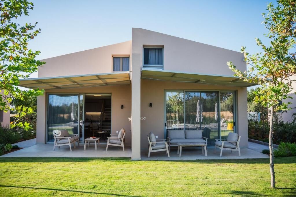 A modern house with a covered patio, large windows, and outdoor seating.