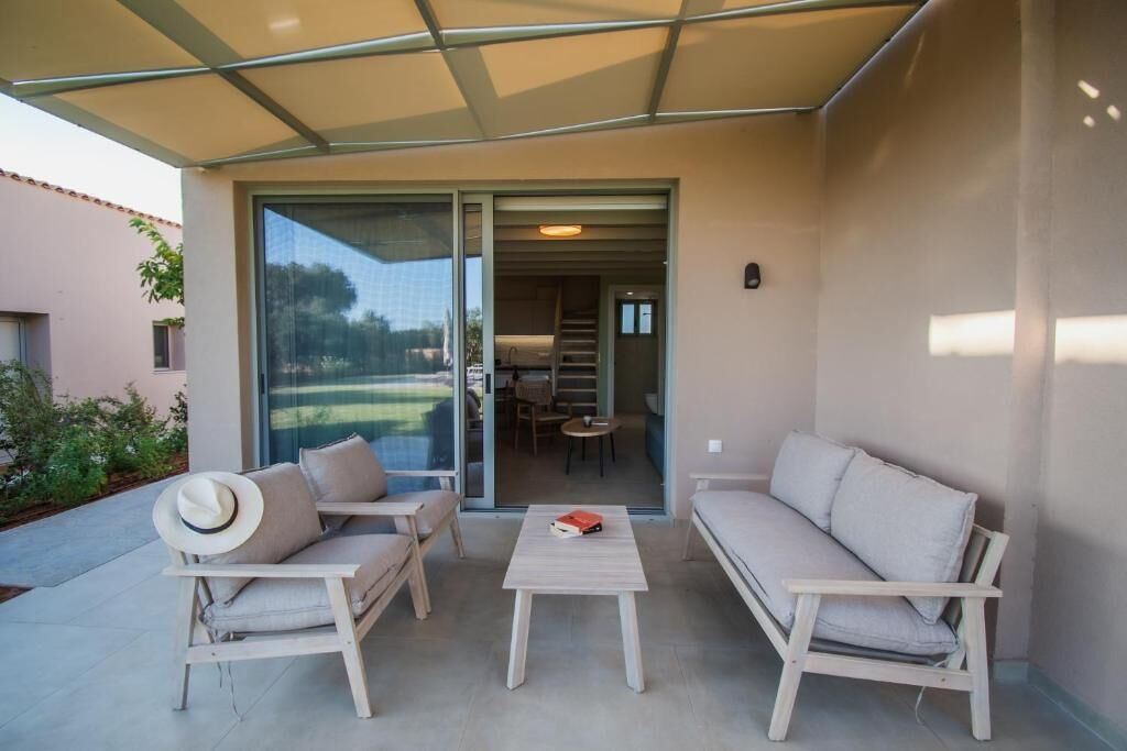 An outdoor seating area with two sofas and a table, a covered patio, and a view into the house.