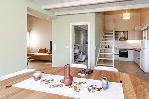A modern kitchen with white cabinets, a stainless steel range hood, and a wooden staircase leading to a loft area.