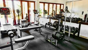 A gym with cardio machines, weight benches, and a rack of dumbbells. - M Club Hotel  (Drawsko Pomorskie)