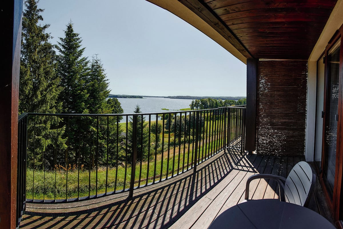 A wooden deck with a view of a lake and forest.