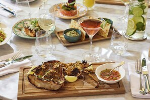 A dining table with a variety of dishes, including grilled meat, a martini, and a bowl of salsa. - Tropical Hotel And Beach (St. Barthelemy)