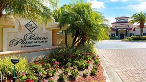 A sign for a condominium named "Postiano Place at Naples" with a landscaped garden in front. - Beautiful 3 Bedroom Condo in Naples, Florida (Naples)