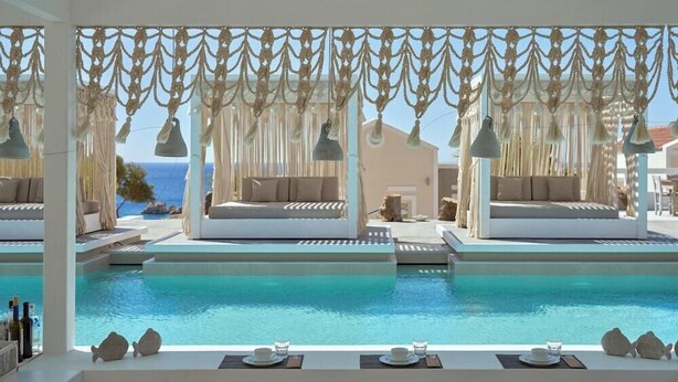 A poolside area with lounge chairs and a view of the sea. - Althea Boutique Hotel (Karpathos)