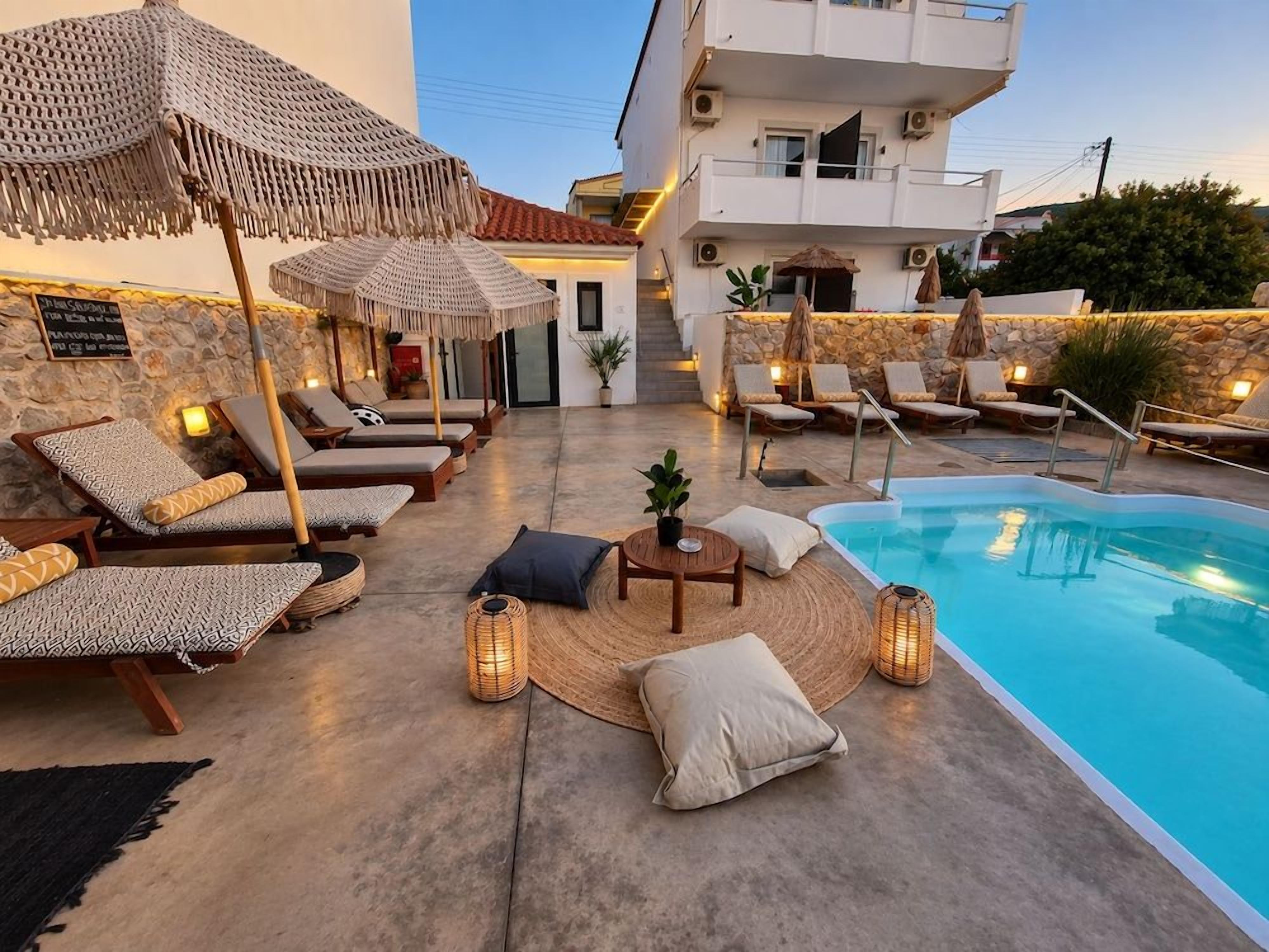 A poolside area with lounge chairs, umbrellas, and a small table with a plant.