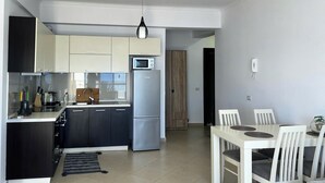 Una cucina moderna con microonde integrato, frigorifero in acciaio inossidabile e zona pranzo con tavolo e sedie bianche.