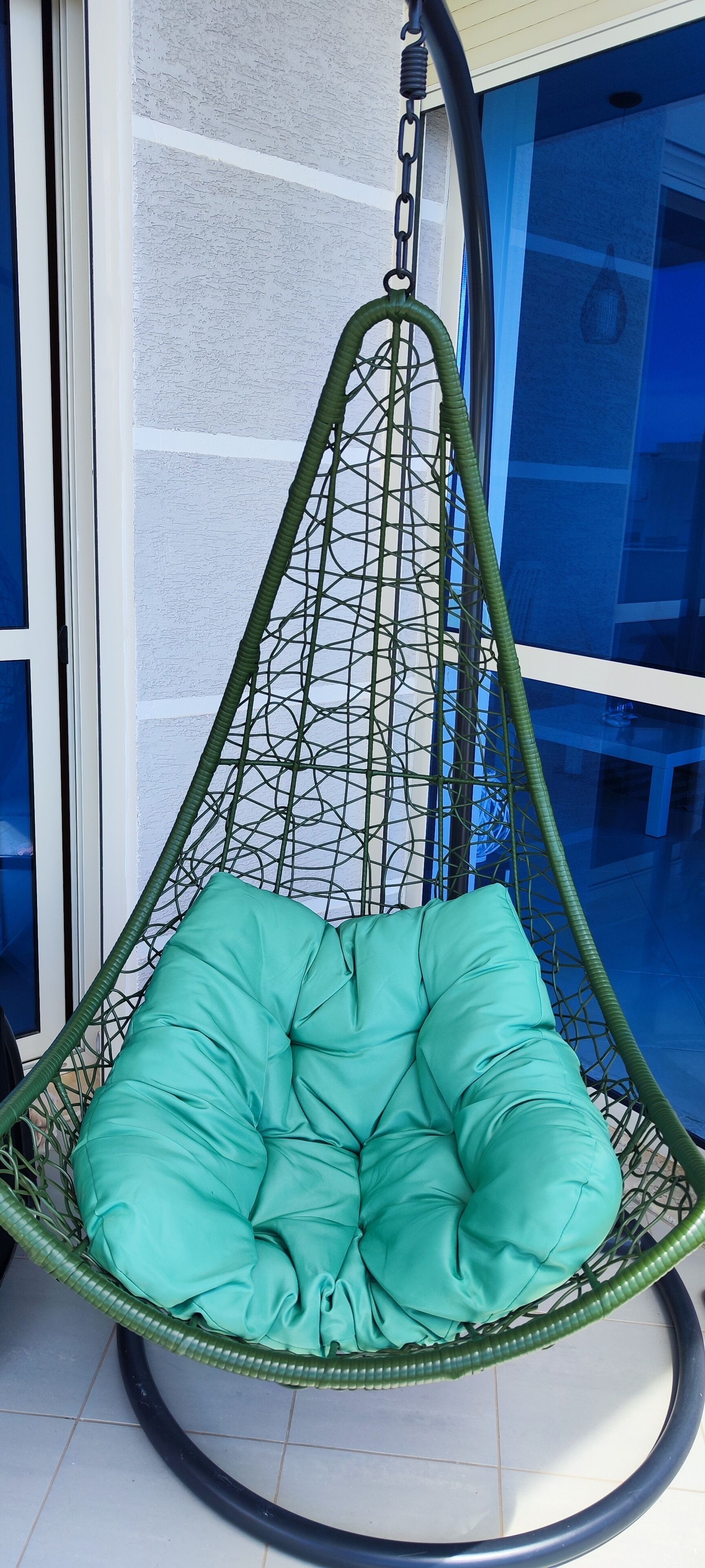 Een groene hangstoel met een zachte zitting.