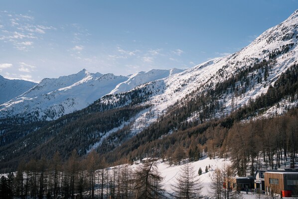 Un paysage de montagne avec des pentes enneigées et un bâtiment à l’architecture moderne.