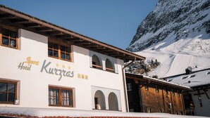 Un edificio blanco con el letrero "Sport Hotel Kitzbühel" y montañas al fondo.