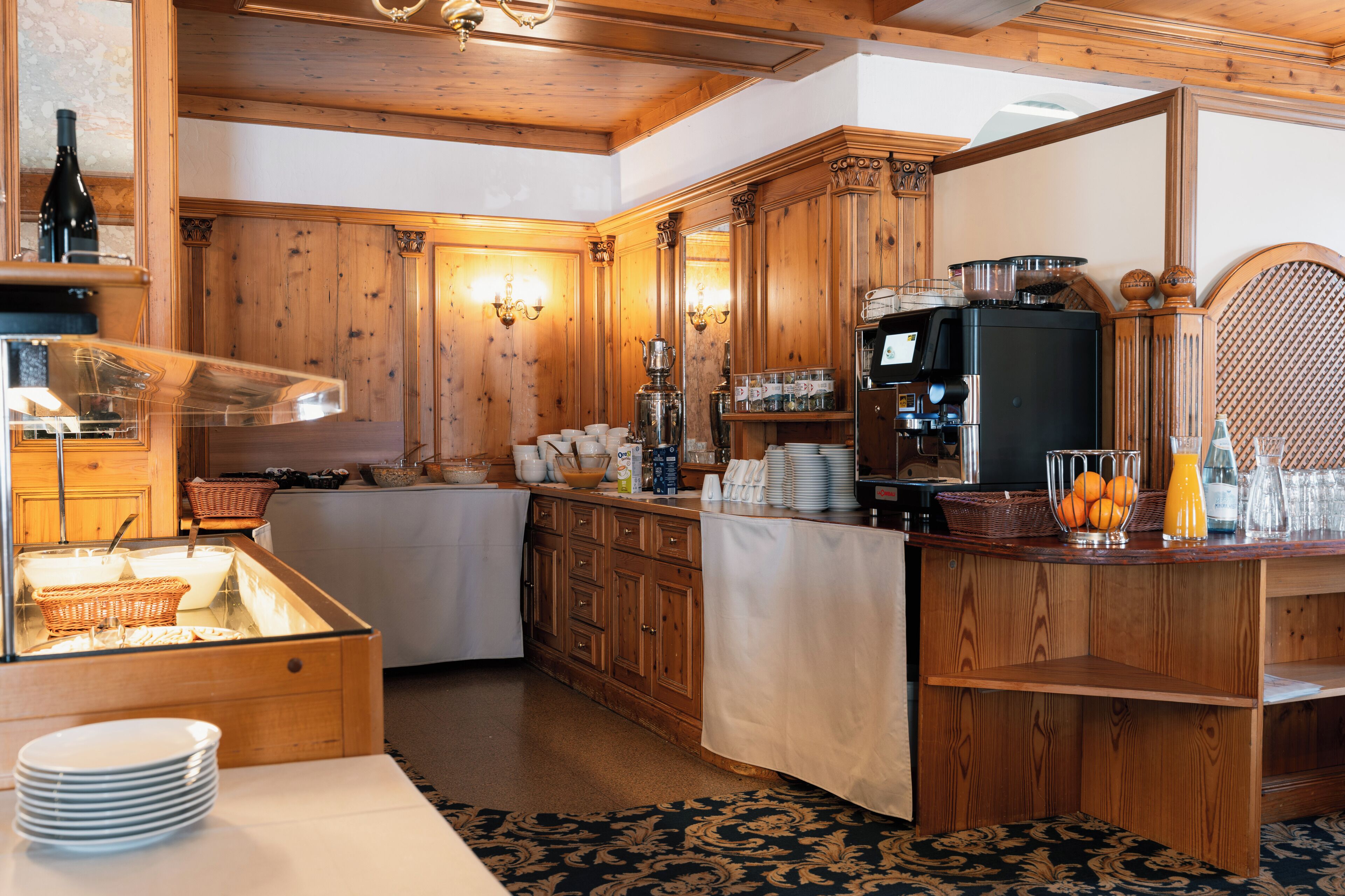 Un interior de madera con una barra de buffet, que incluye un expositor de vidrio, una mesa de buffet y diversos alimentos.