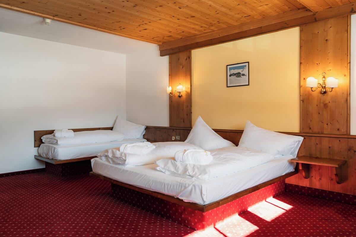 A hotel room with two beds, wooden headboards, and wall-mounted light fixtures.