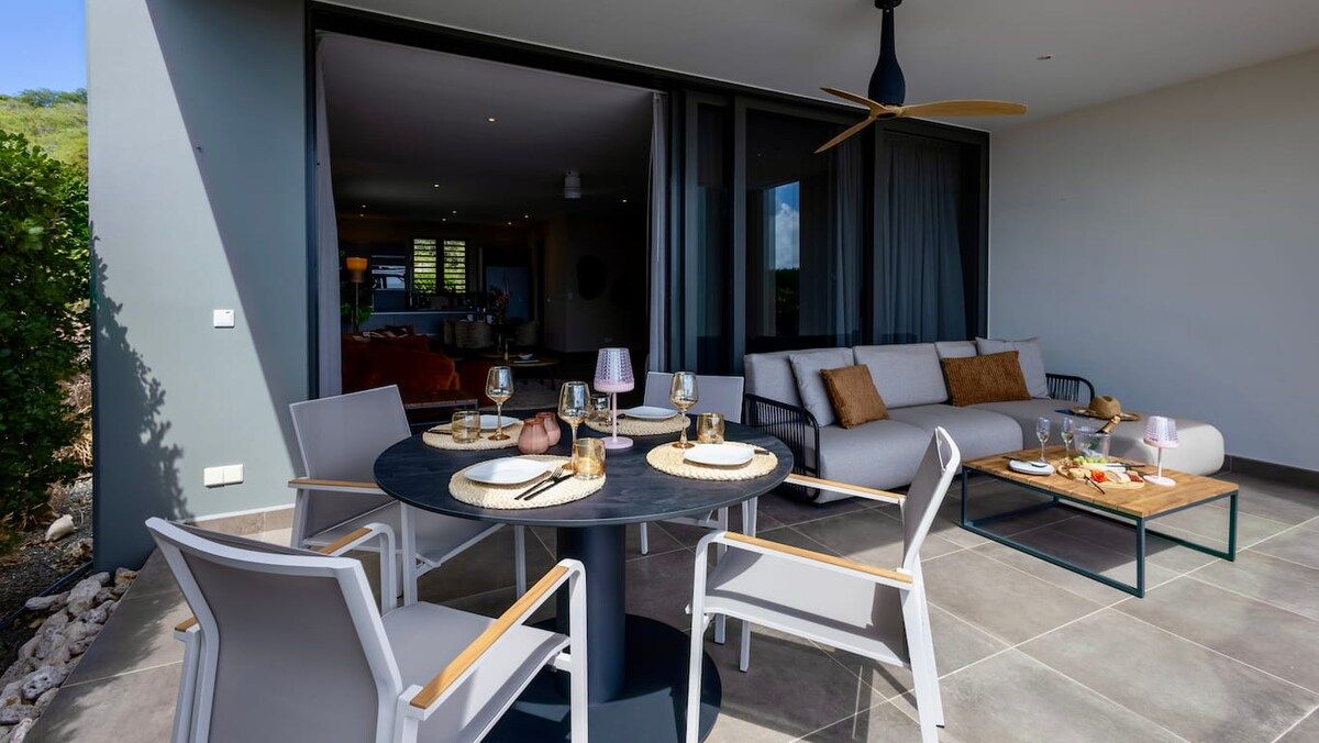 An outdoor dining area with a round table, chairs, and a sofa set.