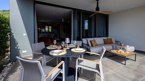 An outdoor dining area with a round table, chairs, and a sofa set. - Luxury ground-floor apartment with tropical calm (Sint Willibrordus)