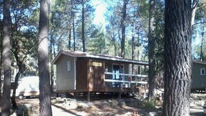 Une cabane avec une façade en bois, une véranda et un panneau indiquant qu’il s’agit d’un terrain de camping.