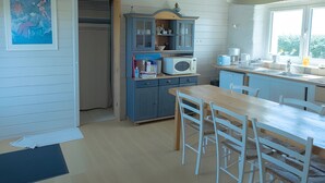 Eine Küche mit Holztisch, Stühlen, einem Schrank und einem Fenster.