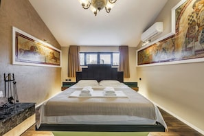 Ett hotellrum med en stor säng, en kristallkrona och konstverk på väggarna.