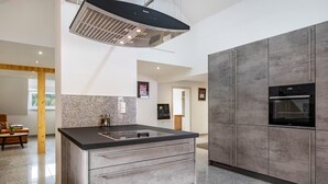 Une cuisine moderne dotée d’un îlot central, d’appareils électroménagers intégrés et d’un design minimaliste.